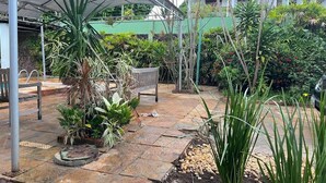 A covered outdoor area with a patio, potted plants, and a bench. - Pousada Jardins (São Luís)