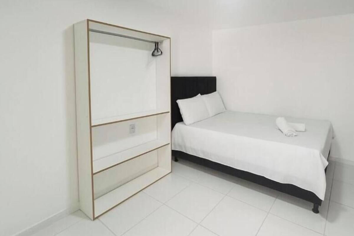 A bedroom with a bed, a wardrobe, and a hanging light fixture.