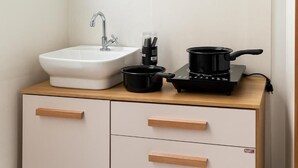 A kitchen with a white sink, a black electric stove, and a wooden countertop. - Pousada Jardins (São Luís)