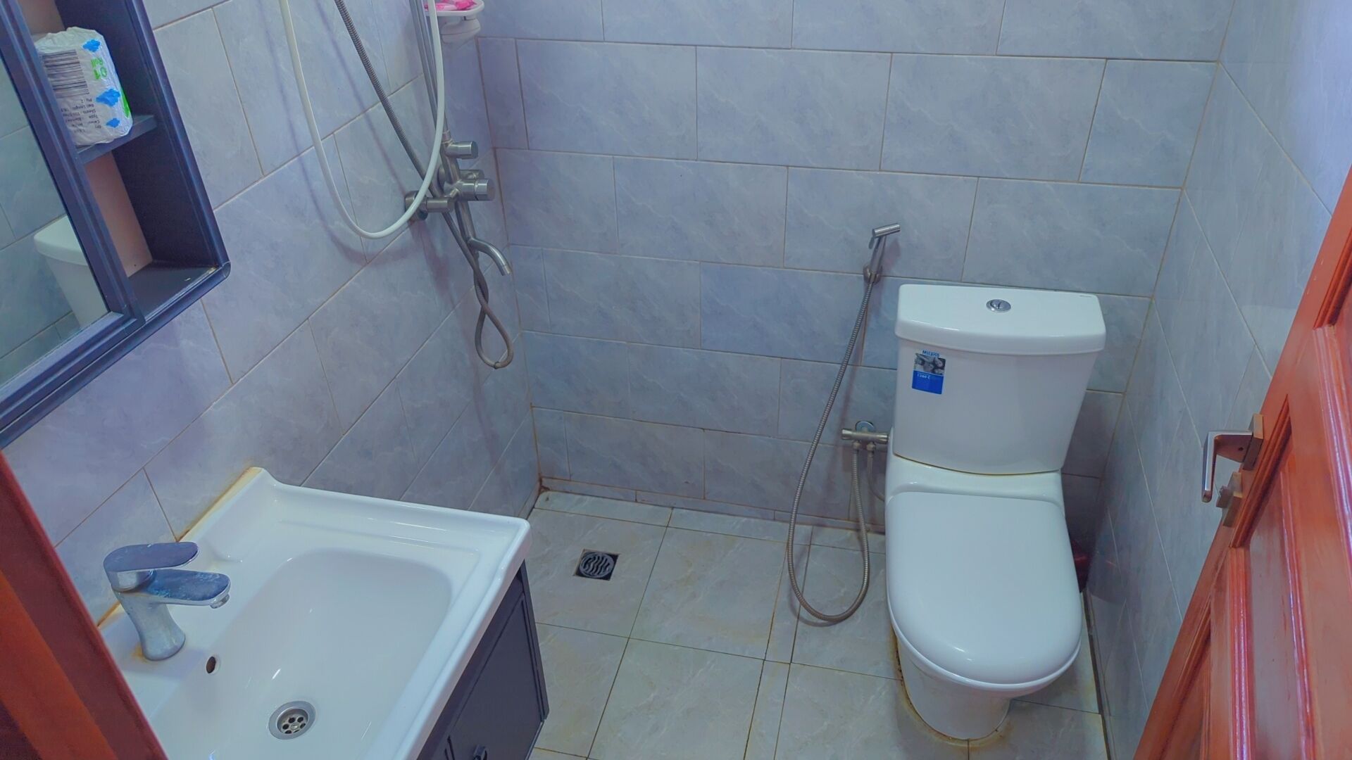 A small bathroom with a white sink, toilet, and shower.