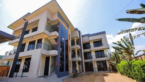 A multi-story building with balconies, a paved courtyard, and a motorcycle parked in front.