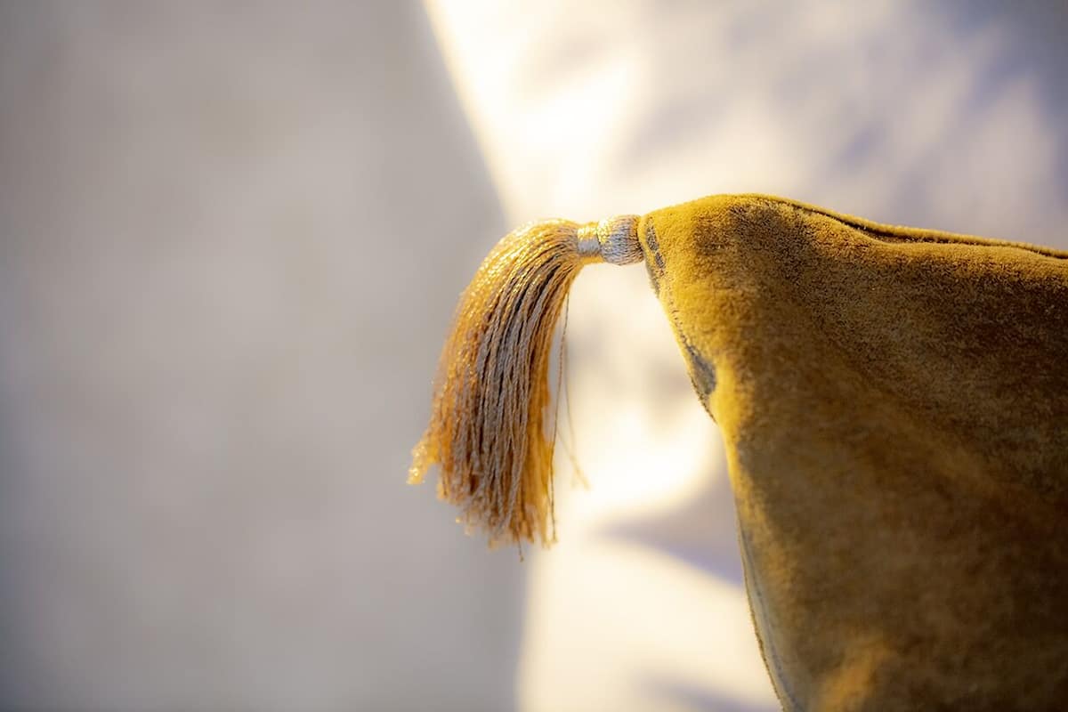 Ein Detailaufnahme einer goldfarbenen Feder auf einem Stoff.