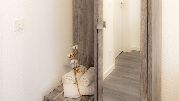 A bathroom with a wooden vanity, a mirror, and towels. - Hotel Zur Feldmühle (Arnsberg)
