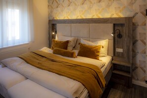 Une chambre à coucher avec un lit, une tête de lit, des tables de chevet et une fenêtre avec des rideaux.