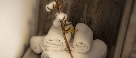 A stack of white towels and a cotton branch on a wooden surface.