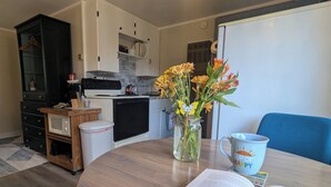 Eine kleine Küche mit Mikrowelle, Spüle und Schränken. Auf dem Tisch steht eine Vase mit Blumen, und ein Buch liegt offen.
