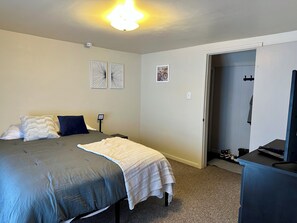 Un dormitorio con cama, escritorio y puerta que da a otra habitación.