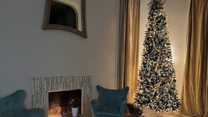 En stue med pejs, to lænestole og et pyntet juletræ.