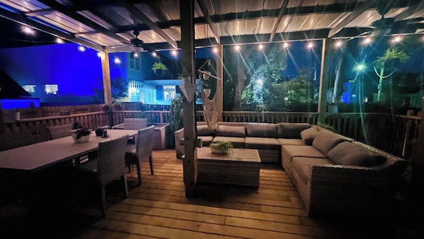 En udendørs terrasse med træterrasse, spisebord med stole og en sofa.