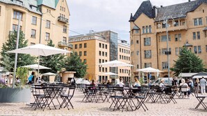 An outdoor café with tables and chairs, surrounded by historic buildings with distinct architectural styles. - Superior Suite by the Sea and Market Square (Helsinki)
