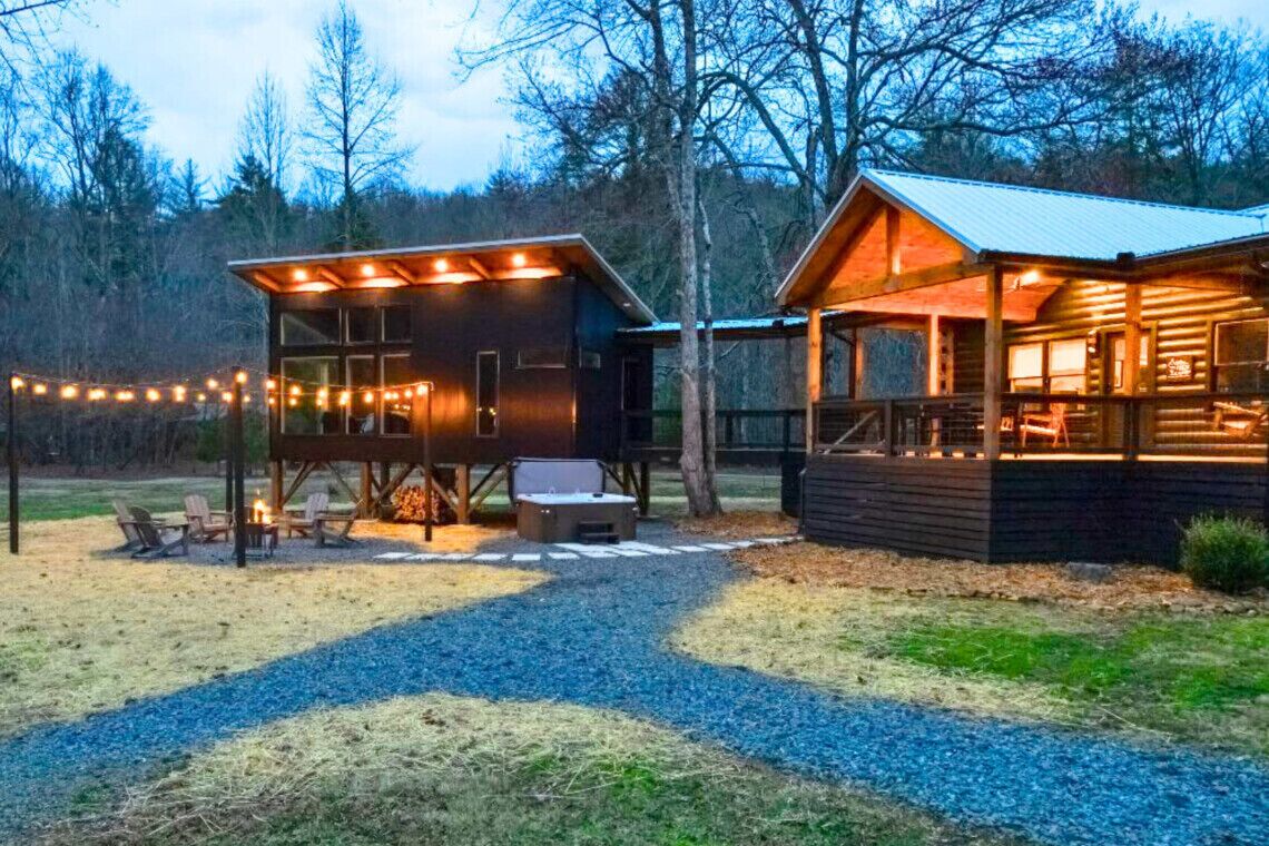 A rustic cabin with a covered outdoor seating area and a separate building with a porch.