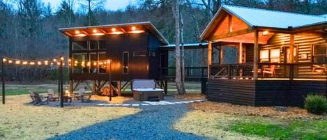 A rustic cabin with a covered outdoor seating area and a separate building with a porch.