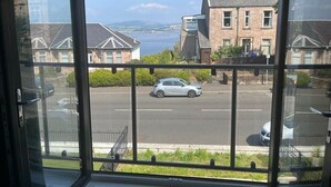 Vista desde una ventana con vista a una calle con coches estacionados y edificios.