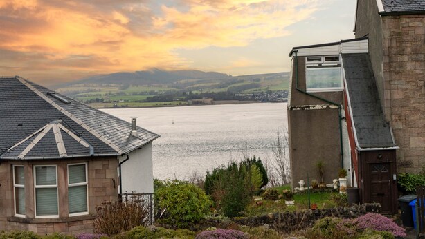Una casa con vista a un lago y colinas al fondo.