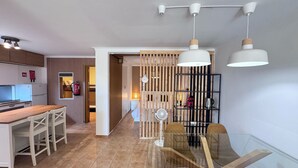 Une cuisine moderne avec une table et des chaises de salle à manger en bois, une table de salle à manger en verre avec des chaises, et un ventilateur de plafond.