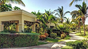 A resort with a covered pool area, palm trees, and a well-maintained garden. - Pueblo Bonito Emerald Luxury Villas & Spa (Mazatlán)
