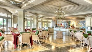 A spacious dining area with high ceilings, chandeliers, and wicker furniture. - Pueblo Bonito Emerald Luxury Villas & Spa (Mazatlán)