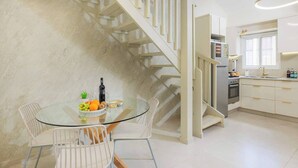 Eine moderne Küche mit Einbauofen, Kühlschrank und Essbereich mit Glastisch und Stühlen.
