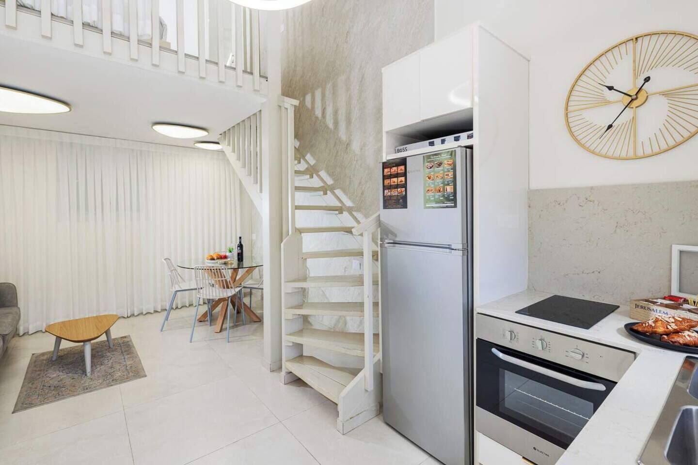 Uma cozinha moderna com forno embutido, geladeira e área de jantar com mesa e cadeiras.