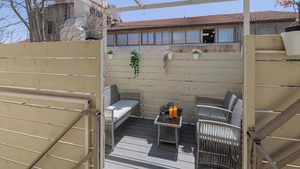 Eine Terrassengaststätte mit einem Metallzaun, einem Tisch mit Stühlen und Blumentöpfen.