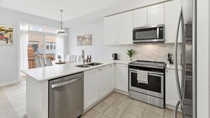 A modern kitchen with white cabinets, stainless steel appliances, and a dishwasher. - Cedar Nest - 5 Beds, 3.5 Baths, 2 Park, Backyard (Pickering)