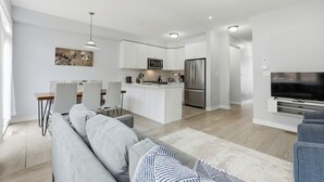 A modern kitchen with white cabinets, a central island, and stainless steel appliances. - Cedar Nest - 5 Beds, 3.5 Baths, 2 Park, Backyard (Pickering)