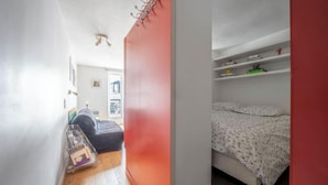 Una habitación estrecha con una cama, un escritorio pequeño y una ventana.