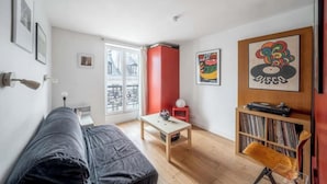 Una sala de estar con un sofá, una mesa de centro, una estantería y una pared de acento roja.