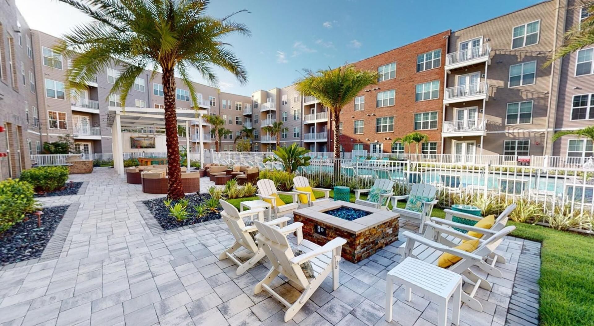 Une cour avec des espaces de détente en plein air, un foyer et une piscine.