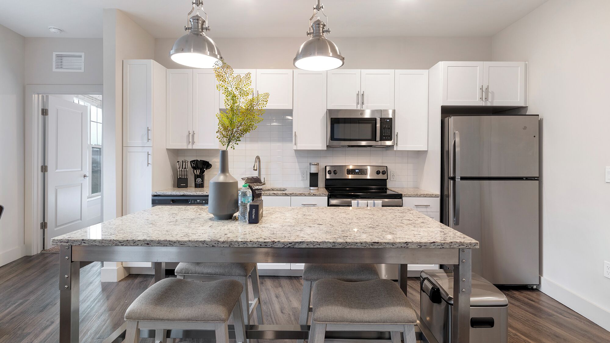 A modern kitchen with a central island, stainless steel appliances, and pendant lighting.