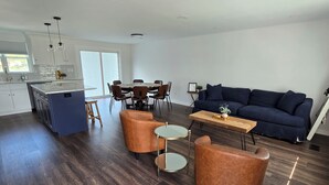 A modern kitchen with a central island, dining area with a round table and chairs, a blue sofa, and two leather armchairs. - Rumsey Island! (Joppatowne)