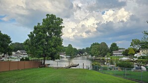 A residential area with a grassy lawn, a body of water, and houses in the background. - Rumsey Island! (Joppatowne)