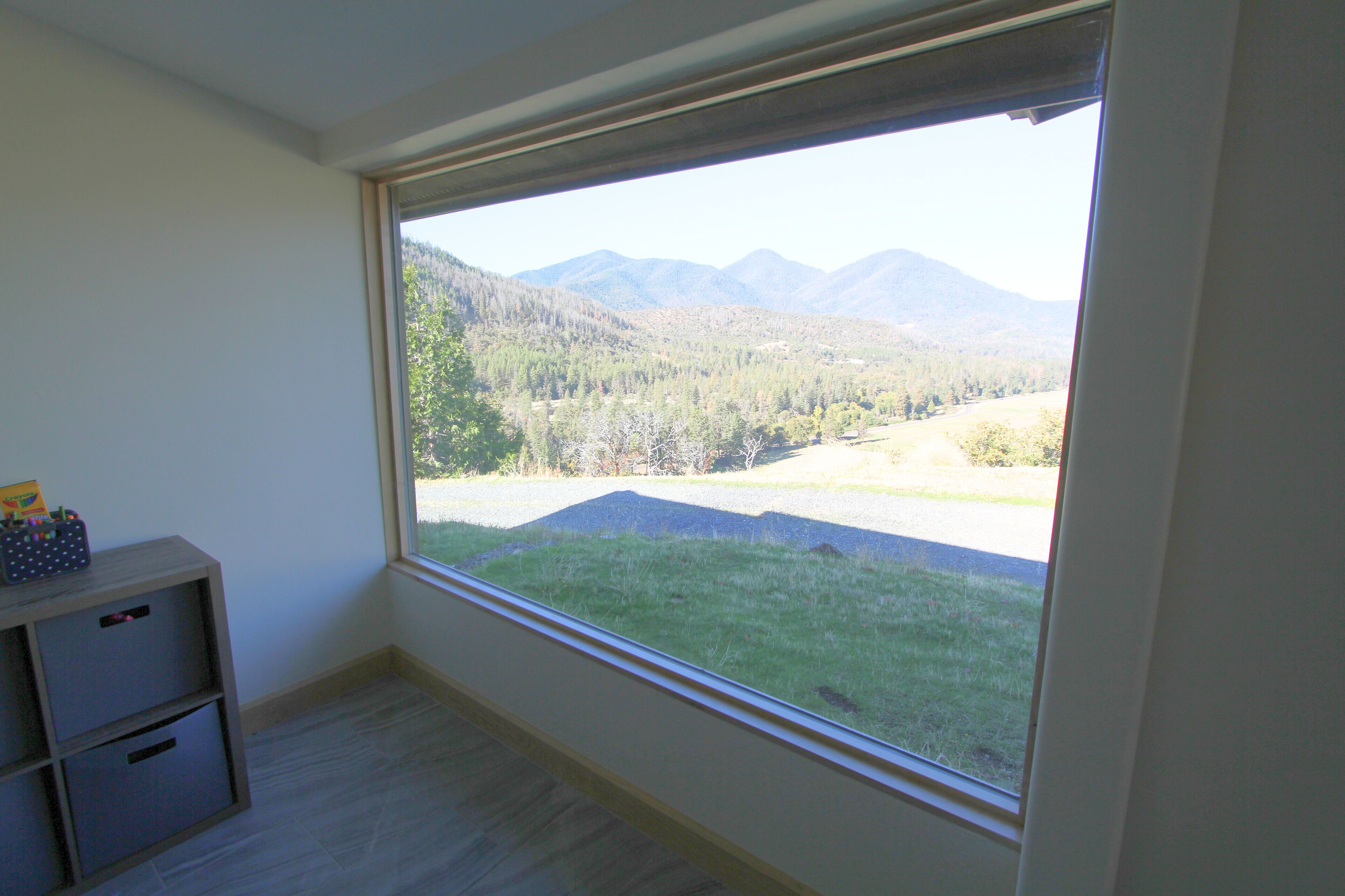 Ein Zimmer mit einem großen Fenster und Blick auf eine gebirgige Landschaft.