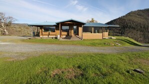 Eine moderne Lodge mit überdachter Veranda, einer Holzterrasse und Blick auf die umliegenden Hügel.