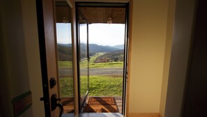 Eine Tür, die zu einem Balkon mit Blick auf eine grüne Landschaft und ferne Berge führt.