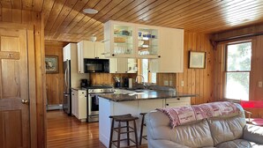 Una cocina con paneles de madera, armarios blancos, una estufa de acero inoxidable y una isla grande con taburetes.