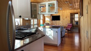 Una cocina compacta con estufa, alacenas y un mueble superior con puerta de vidrio.