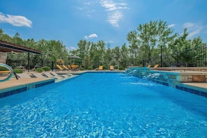 A clear blue pool with lounge chairs and a small waterfall feature.