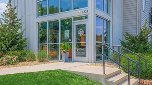 A modern building with a glass entrance, a sign indicating office hours, and a number 2621. - Landing Spectacular 1bd, Courtyard (Springfield)