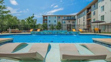 A swimming pool with lounge chairs and a stone wall in the background.