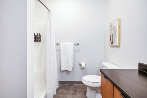 A bathroom with a shower, toilet, and a towel rack.