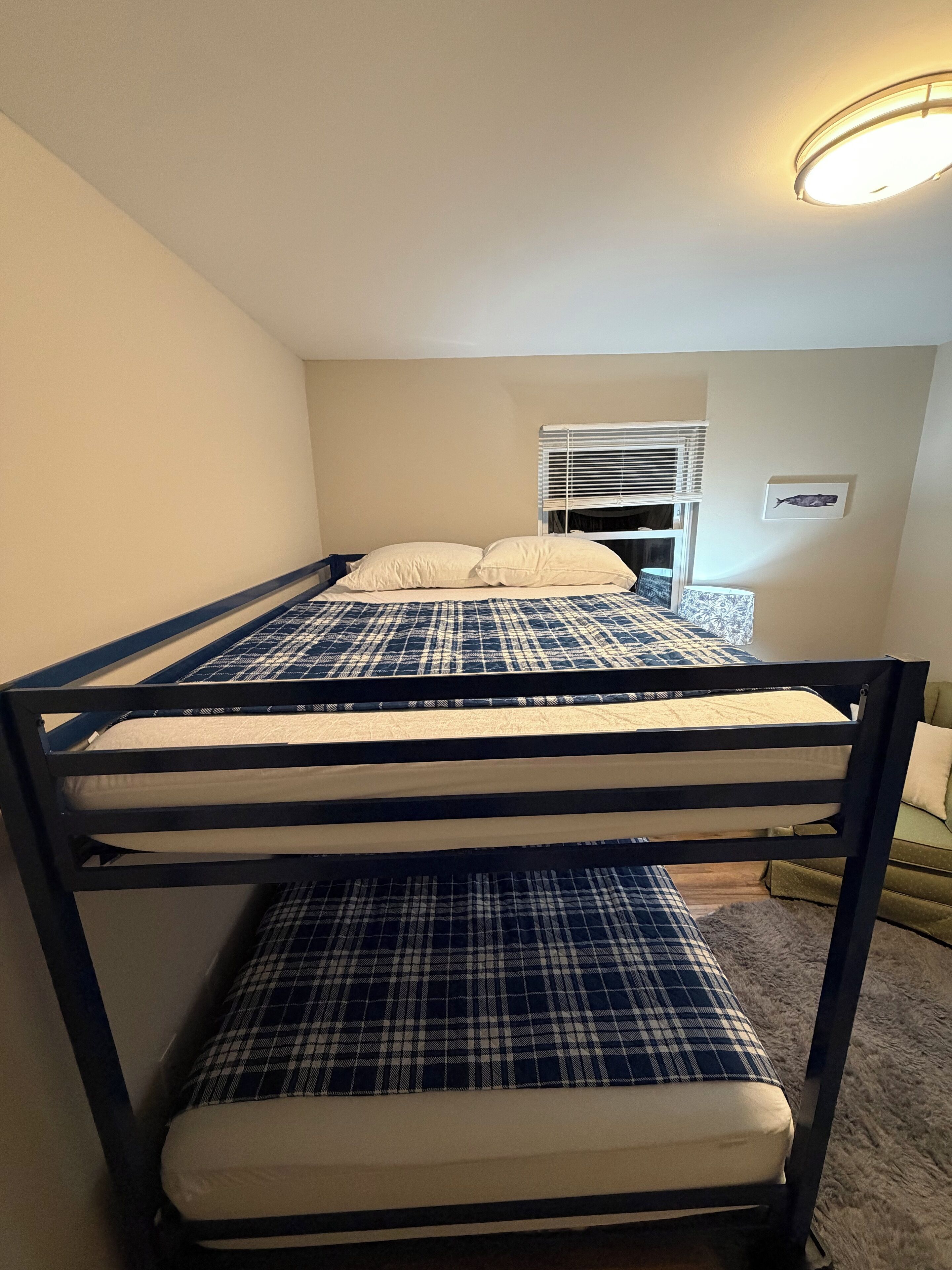 A bunk bed with a blue and white checkered bedspread and white pillows.