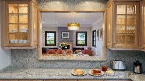 Una cocina con encimeras de granito, armarios de madera y un comedor con sillas y una mesa.