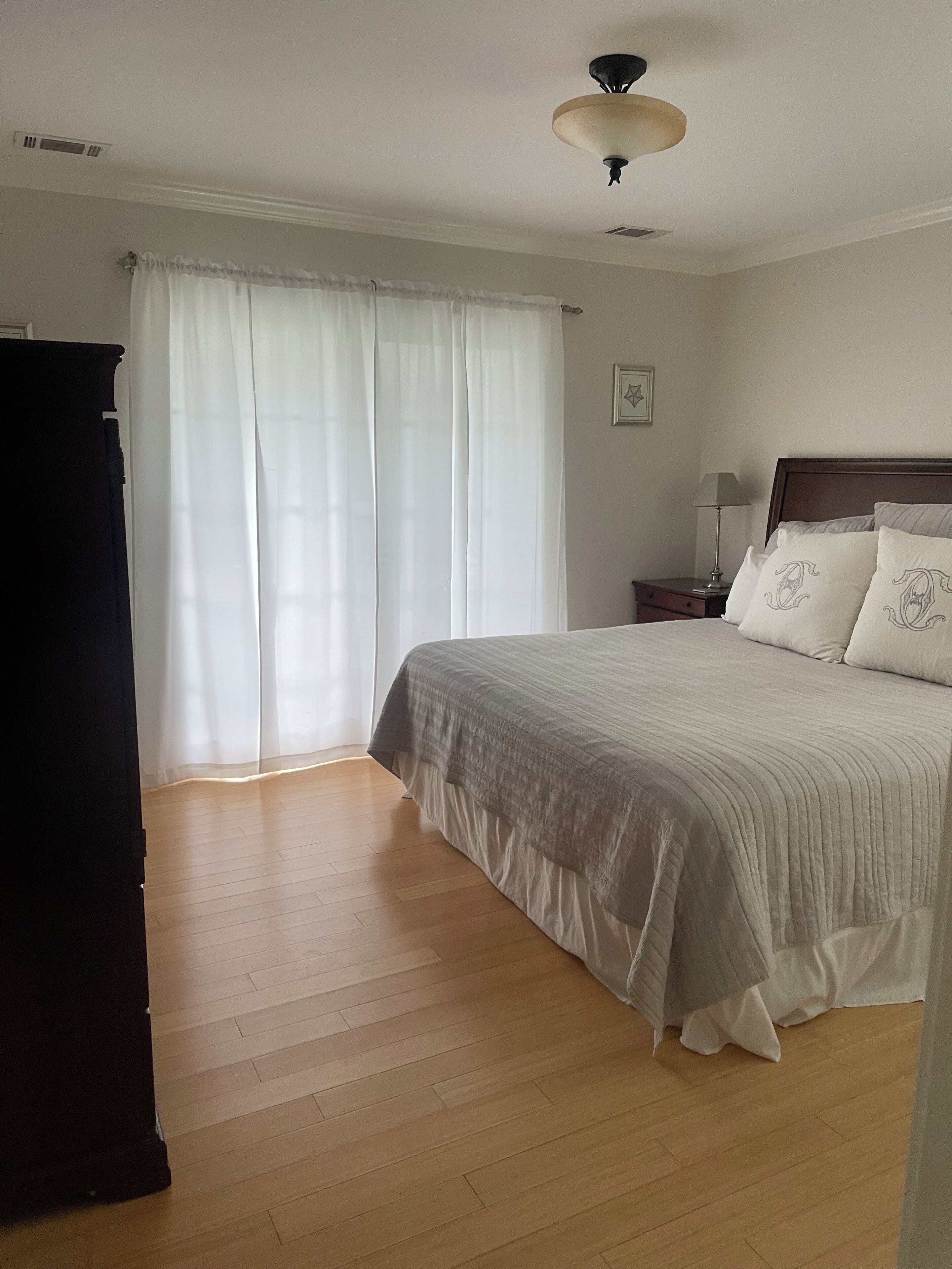 A bedroom with a bed, a nightstand, a lamp, and a window with curtains.