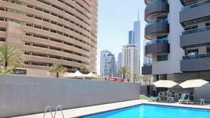 A modern building with a pool area, including lounge chairs and umbrellas. - 35 OFF in Top View Studio in Marina (Dubai)