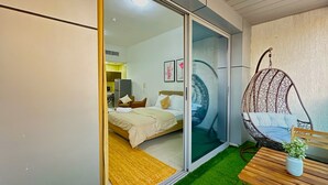 A modern bedroom with a sliding glass door leading to a kitchen, a hanging chair, and a small table with a plant. - 35 OFF in Top View Studio in Marina (Dubai)