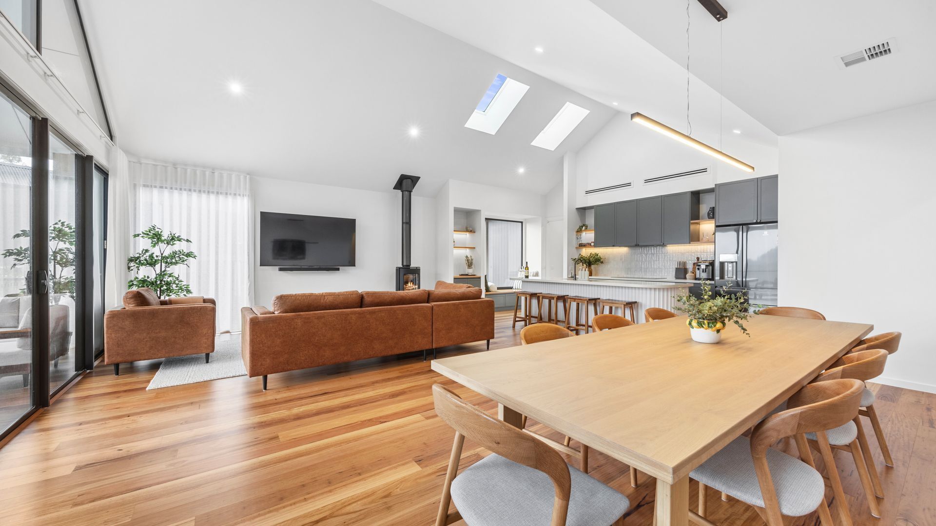 A modern living room with a wooden dining table, sofa, and TV.