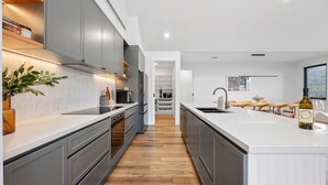 Une cuisine moderne avec des meubles gris, un plan de travail blanc et un plancher en bois.