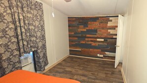 Una habitación con cortina estampada, panel de pared de madera y una puerta.