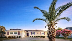 A two-story house with a front porch, a palm tree, and a well-maintained lawn. - Grand Lagoon Retreat | Blue Angels & Boat Parking (Pensacola)
